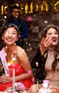 2 women smiling and celebrating a birthday party with glitter in the air